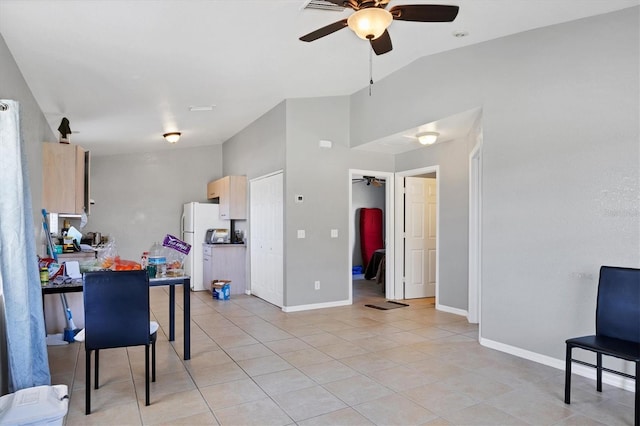 kitchen with vaulted ceiling, white refrigerator, light tile patterned floors, ceiling fan, and light brown cabinets