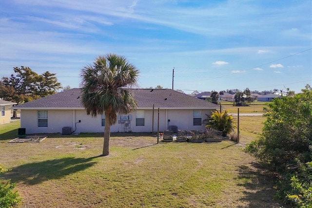 rear view of house with cooling unit and a lawn