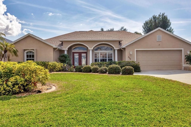 ranch-style home featuring a garage, a front yard, and french doors