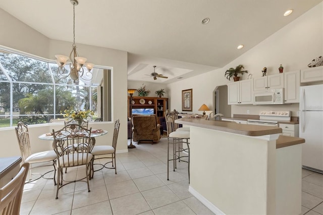 kitchen featuring white appliances, an island with sink, white cabinets, ceiling fan with notable chandelier, and decorative light fixtures