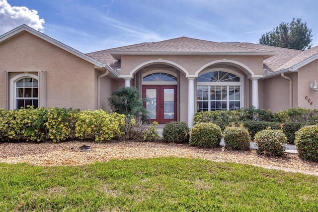 view of exterior entry with french doors and a lawn