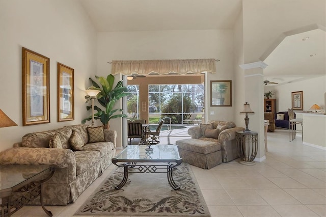 tiled living room featuring ceiling fan, decorative columns, and a high ceiling