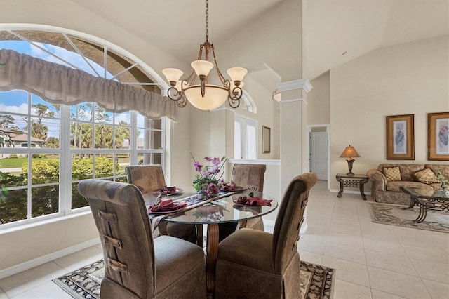 tiled dining room featuring a notable chandelier, decorative columns, and high vaulted ceiling