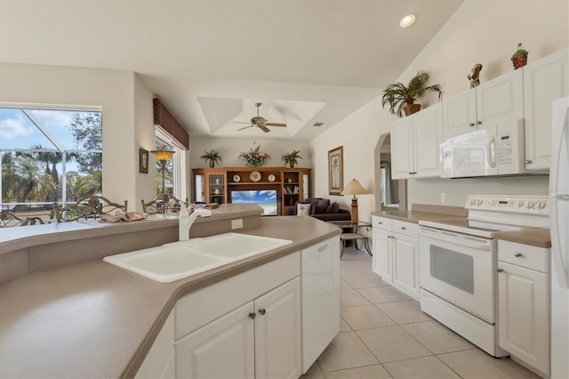 kitchen with sink, white appliances, light tile patterned floors, white cabinetry, and a tray ceiling