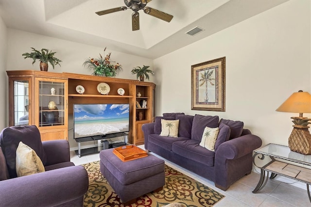 living room with a raised ceiling, light tile patterned floors, and ceiling fan