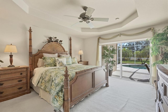 carpeted bedroom featuring a tray ceiling, access to outside, and ceiling fan