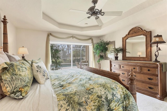 bedroom with access to outside, ceiling fan, and a tray ceiling