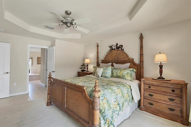 bedroom with ceiling fan, ensuite bath, a raised ceiling, and light tile patterned floors