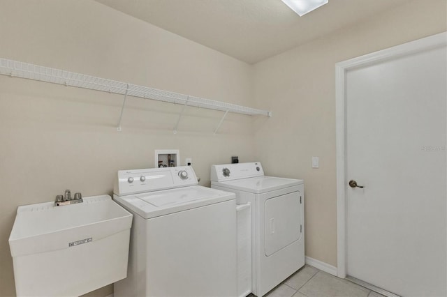 clothes washing area featuring washing machine and clothes dryer, sink, and light tile patterned floors