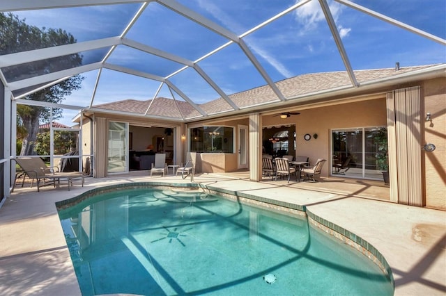 view of pool featuring ceiling fan, glass enclosure, and a patio area