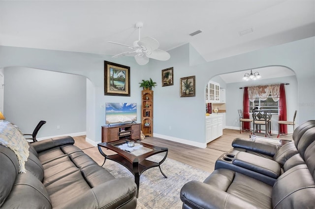 living room featuring vaulted ceiling, ceiling fan with notable chandelier, and light wood-type flooring