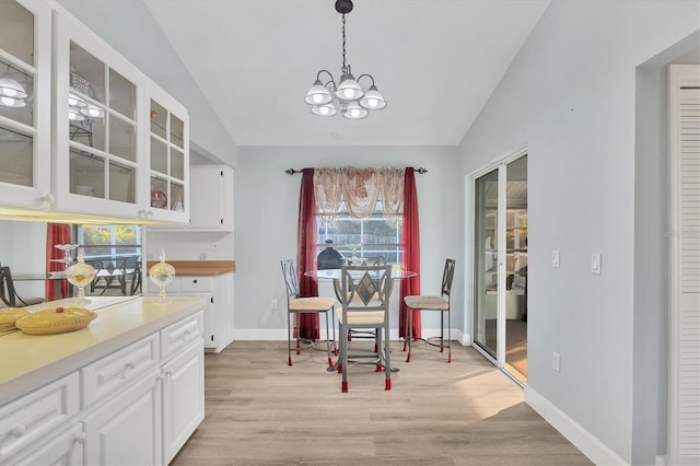 dining room with lofted ceiling, light hardwood / wood-style floors, and a notable chandelier