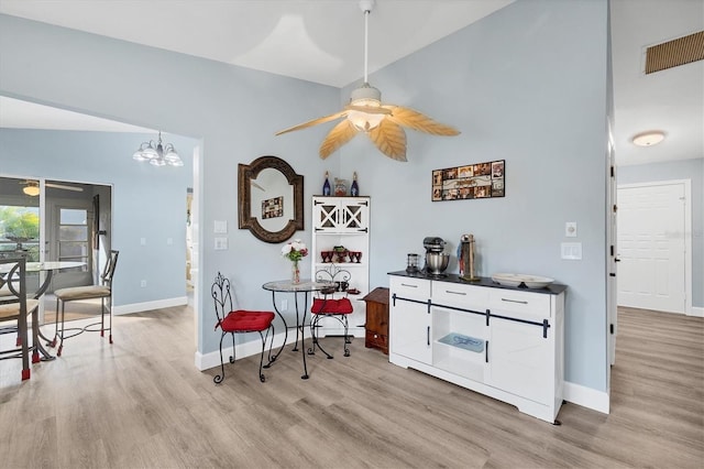 dining room featuring ceiling fan with notable chandelier and light hardwood / wood-style floors