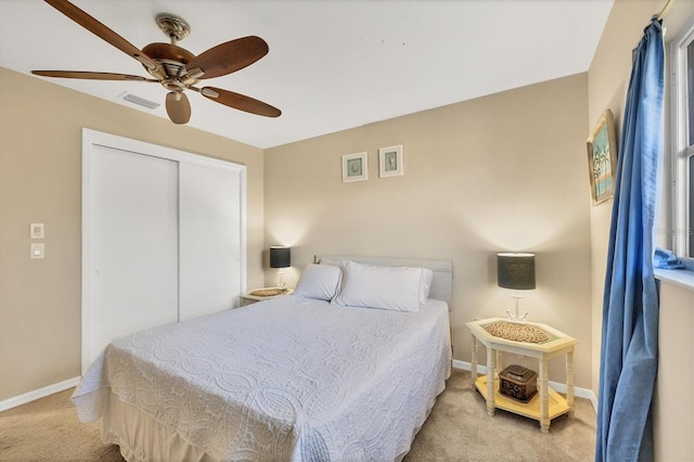 bedroom with light colored carpet, ceiling fan, and a closet