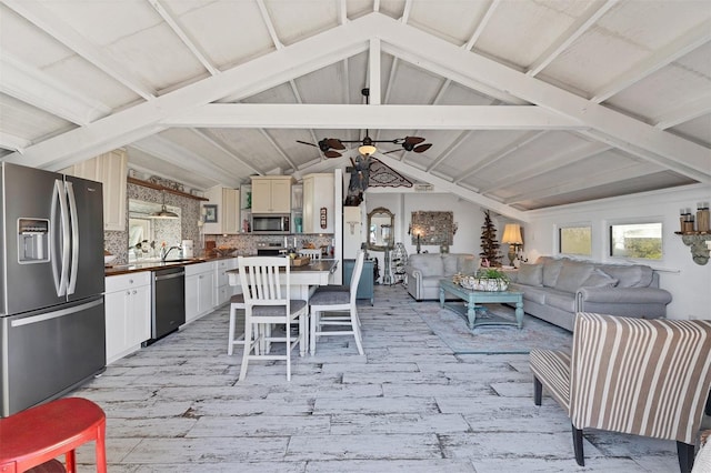 interior space with vaulted ceiling, sink, ceiling fan, and light hardwood / wood-style flooring