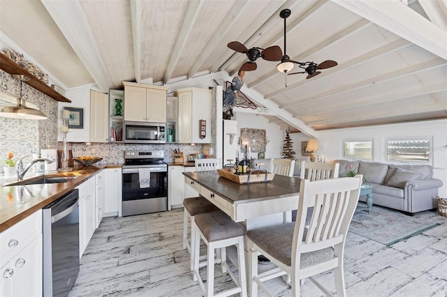 kitchen featuring wood counters, sink, pendant lighting, and stainless steel appliances