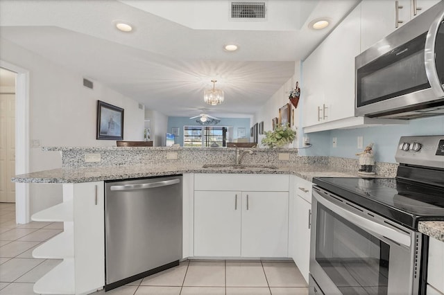 kitchen with light tile patterned flooring, appliances with stainless steel finishes, sink, white cabinets, and kitchen peninsula