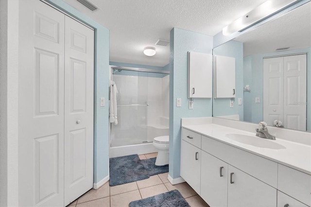 bathroom featuring tile patterned floors, toilet, a textured ceiling, vanity, and a shower with door