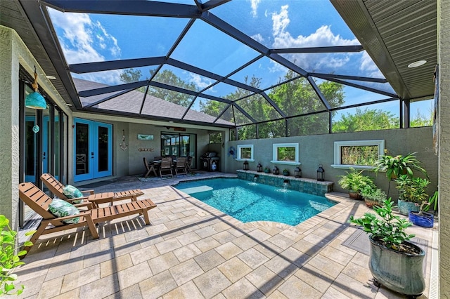 view of swimming pool with french doors, pool water feature, ceiling fan, glass enclosure, and a patio area