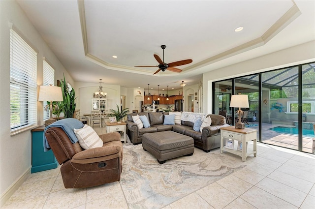 tiled living room featuring a raised ceiling and ceiling fan with notable chandelier