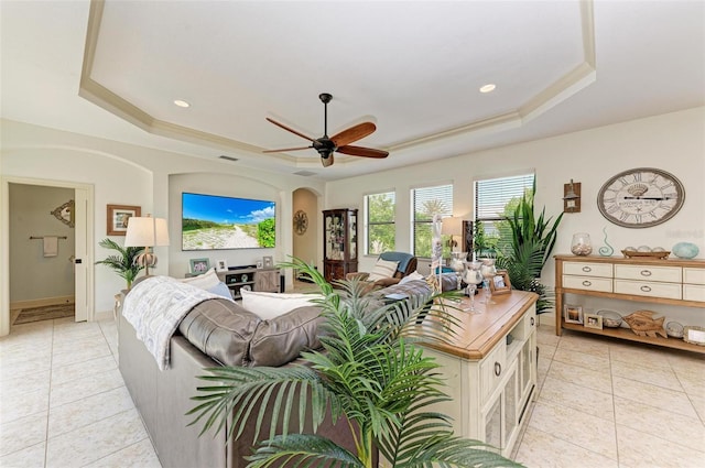 tiled living room featuring a raised ceiling, ornamental molding, and ceiling fan