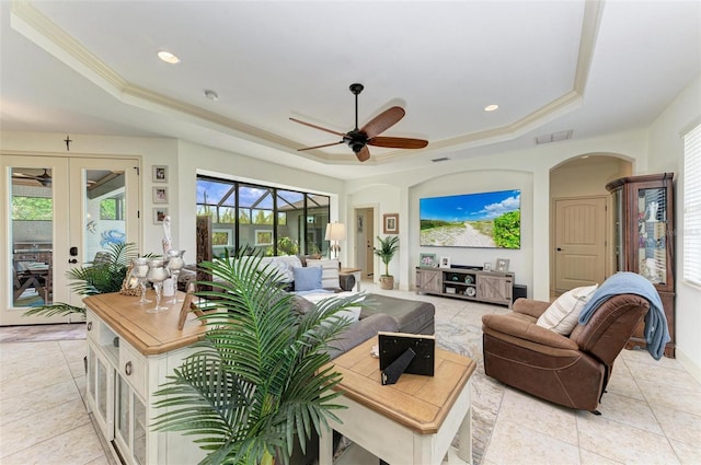 tiled living room with crown molding, ceiling fan, a tray ceiling, and french doors