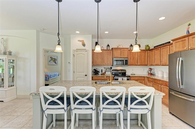 kitchen featuring appliances with stainless steel finishes, a kitchen island with sink, sink, and decorative light fixtures