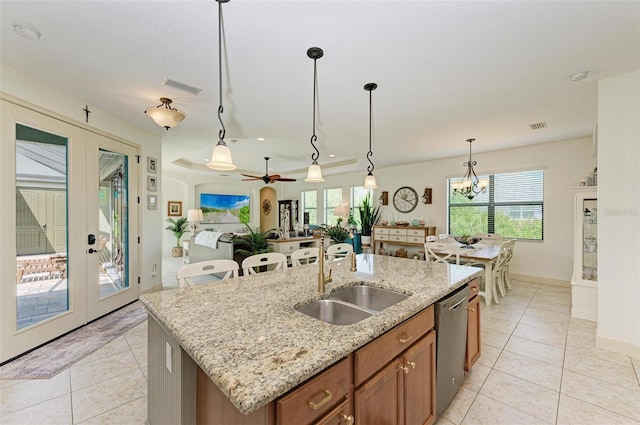 kitchen with pendant lighting, dishwasher, an island with sink, sink, and french doors