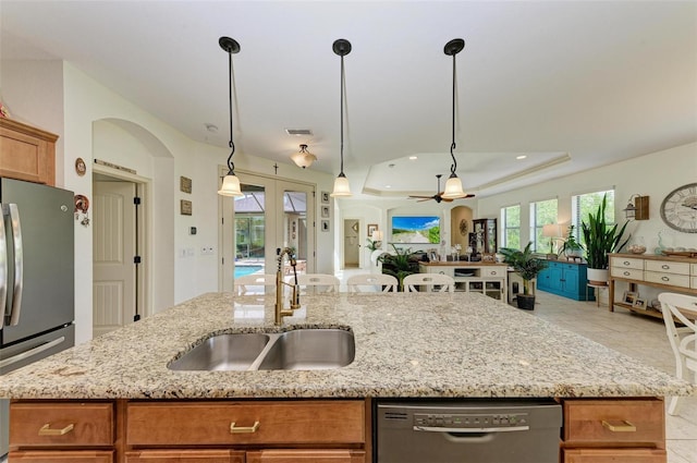 kitchen featuring light stone counters, sink, decorative light fixtures, and stainless steel appliances