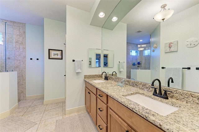 bathroom with a tile shower, vanity, and tile patterned floors