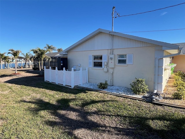 view of side of home with fence and a yard