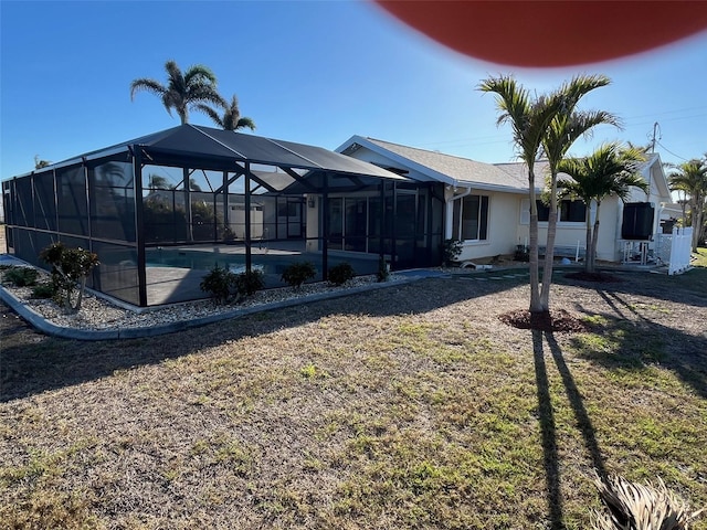 back of property featuring glass enclosure, an outdoor pool, and stucco siding