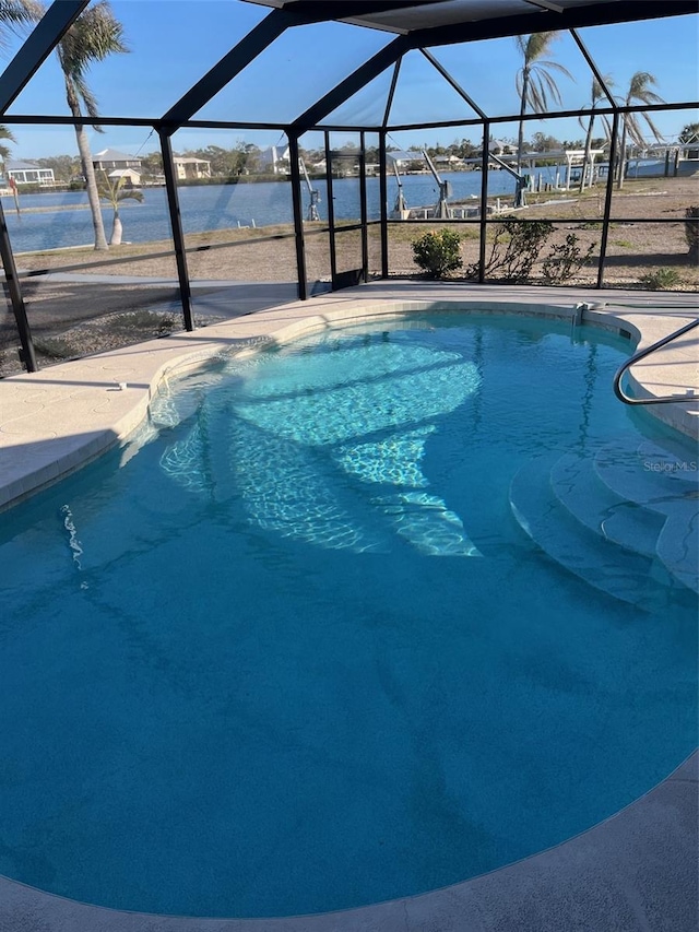 outdoor pool featuring a lanai, a water view, and a patio