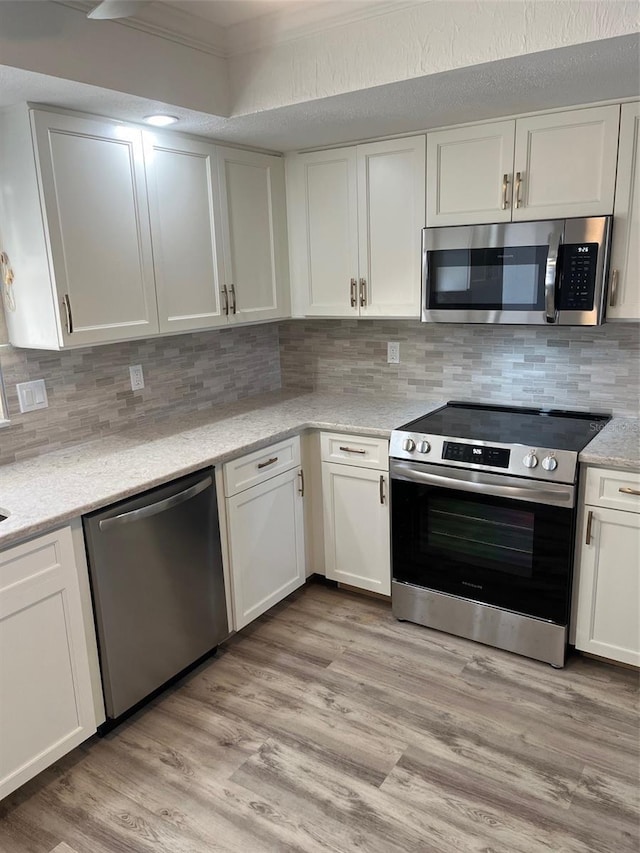 kitchen featuring appliances with stainless steel finishes, white cabinets, and light wood-style flooring