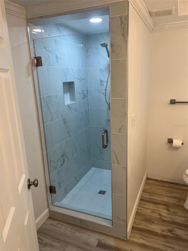 full bathroom with toilet, a shower stall, baseboards, and wood finished floors