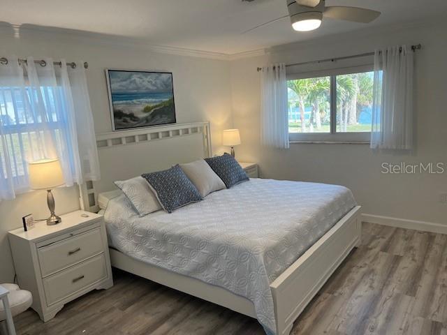 bedroom featuring ceiling fan, ornamental molding, wood finished floors, and baseboards