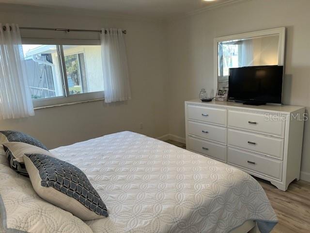 bedroom featuring ornamental molding, wood finished floors, and baseboards