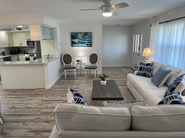 living room with light wood-style flooring, baseboards, and ceiling fan