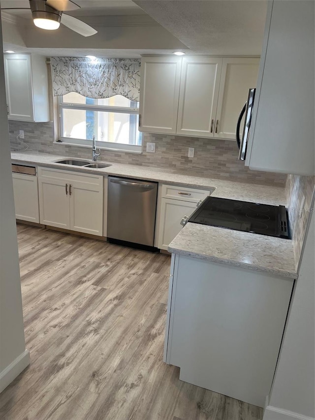 kitchen with a sink, white cabinetry, stainless steel dishwasher, decorative backsplash, and light wood finished floors