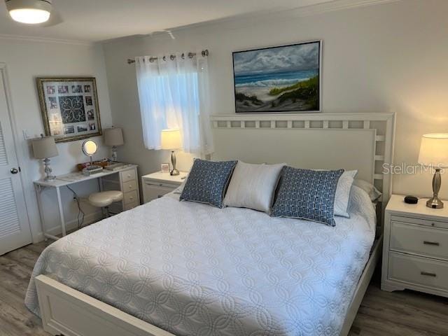 bedroom with ornamental molding and wood finished floors