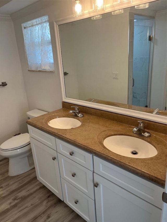 full bathroom with toilet, double vanity, a sink, and wood finished floors