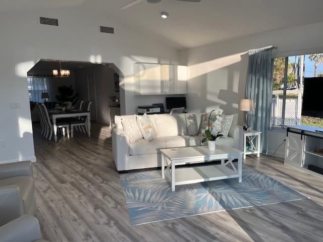 living room with visible vents, vaulted ceiling, and wood finished floors