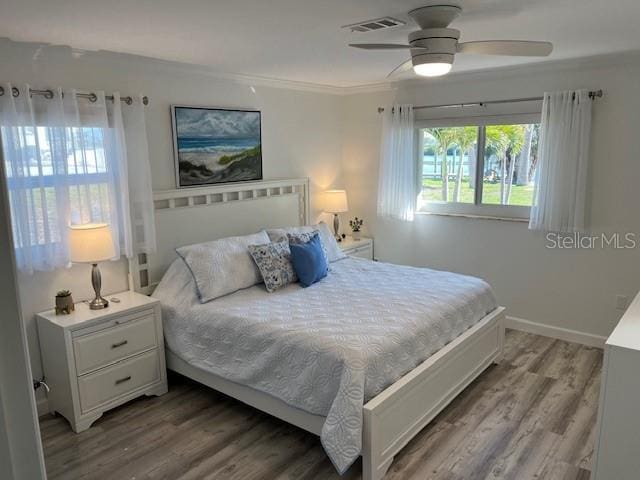 bedroom with visible vents, crown molding, ceiling fan, and wood finished floors