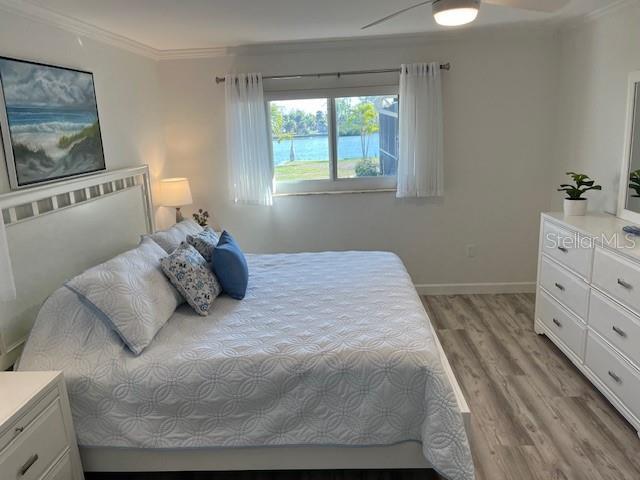 bedroom with baseboards, wood finished floors, ornamental molding, and a ceiling fan