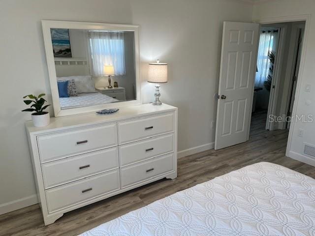 bedroom with visible vents, baseboards, and wood finished floors