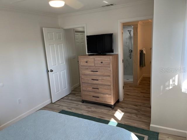 bedroom featuring crown molding, light wood-style flooring, baseboards, and visible vents