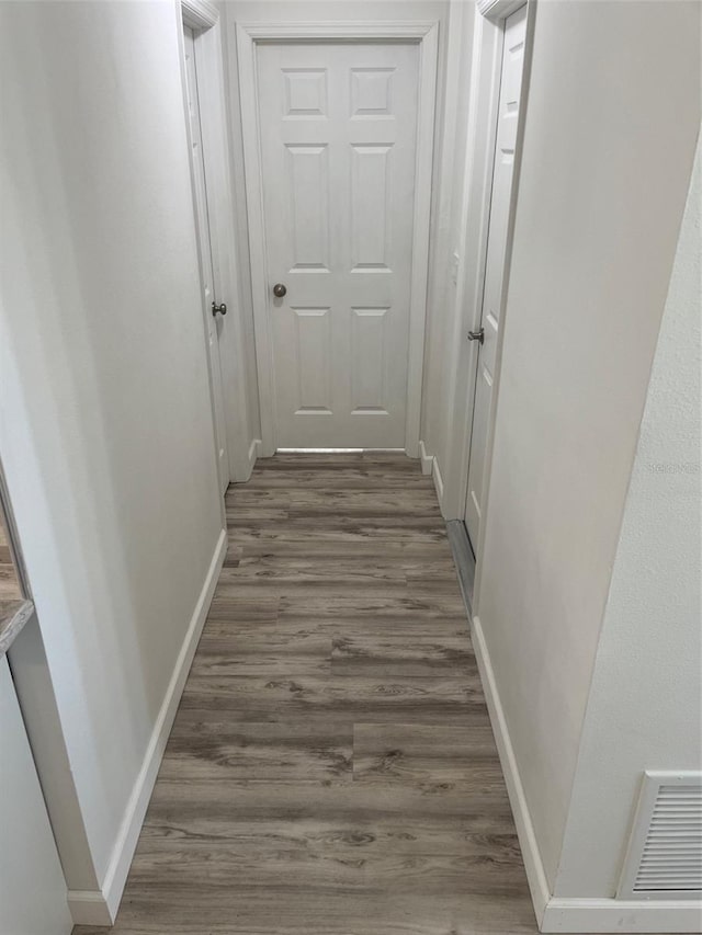 corridor featuring dark wood-style floors, visible vents, and baseboards