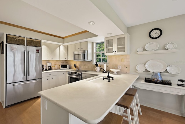 kitchen with sink, a breakfast bar area, kitchen peninsula, stainless steel appliances, and backsplash