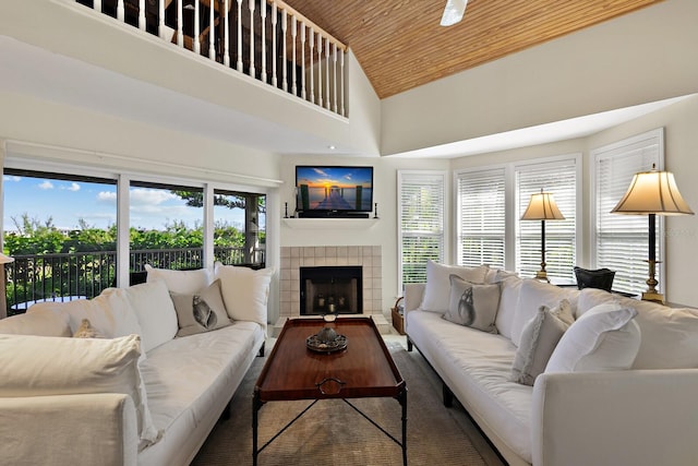 living room featuring a towering ceiling, wooden ceiling, and a tile fireplace