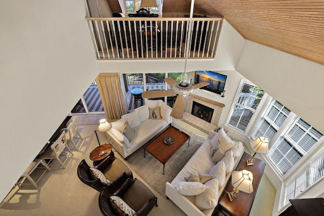 living room with a high ceiling, a tiled fireplace, wooden ceiling, and ceiling fan